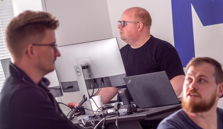 IT konsulenter hjælper hinanden i kontoret med at finde gode løsninger for kunder